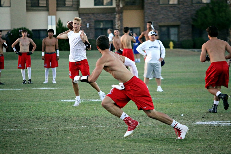 Football player prepares to throw a football as another player prepares to catch it